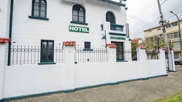 A white building with a sign that reads "HOTEL" and a smaller sign above it that says "The Tea House."