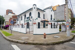 A white building with a sign indicating it's a hotel. There is a fire hydrant in front of the building. - Ayenda La Tua Casa (Bogotá)