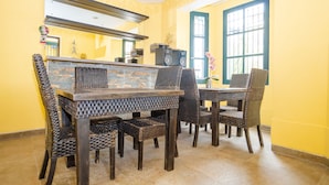 A dining area with a stone-tiled floor, a dark wooden table, and wicker chairs. - Ayenda La Tua Casa (Bogotá)