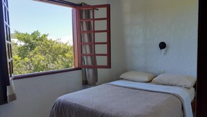 A bedroom with a bed, a window with curtains, and a view of trees outside. - Hostal Blanco Apart-Hotel (Florianópolis)