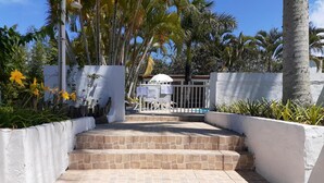 A set of stone steps leading to a white wall, surrounded by palm trees and a pool area. - Hostal Blanco Apart-Hotel (Florianópolis)