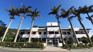 A multi-story building with a white facade, surrounded by palm trees. - Hostal Blanco Apart-Hotel (Florianópolis)