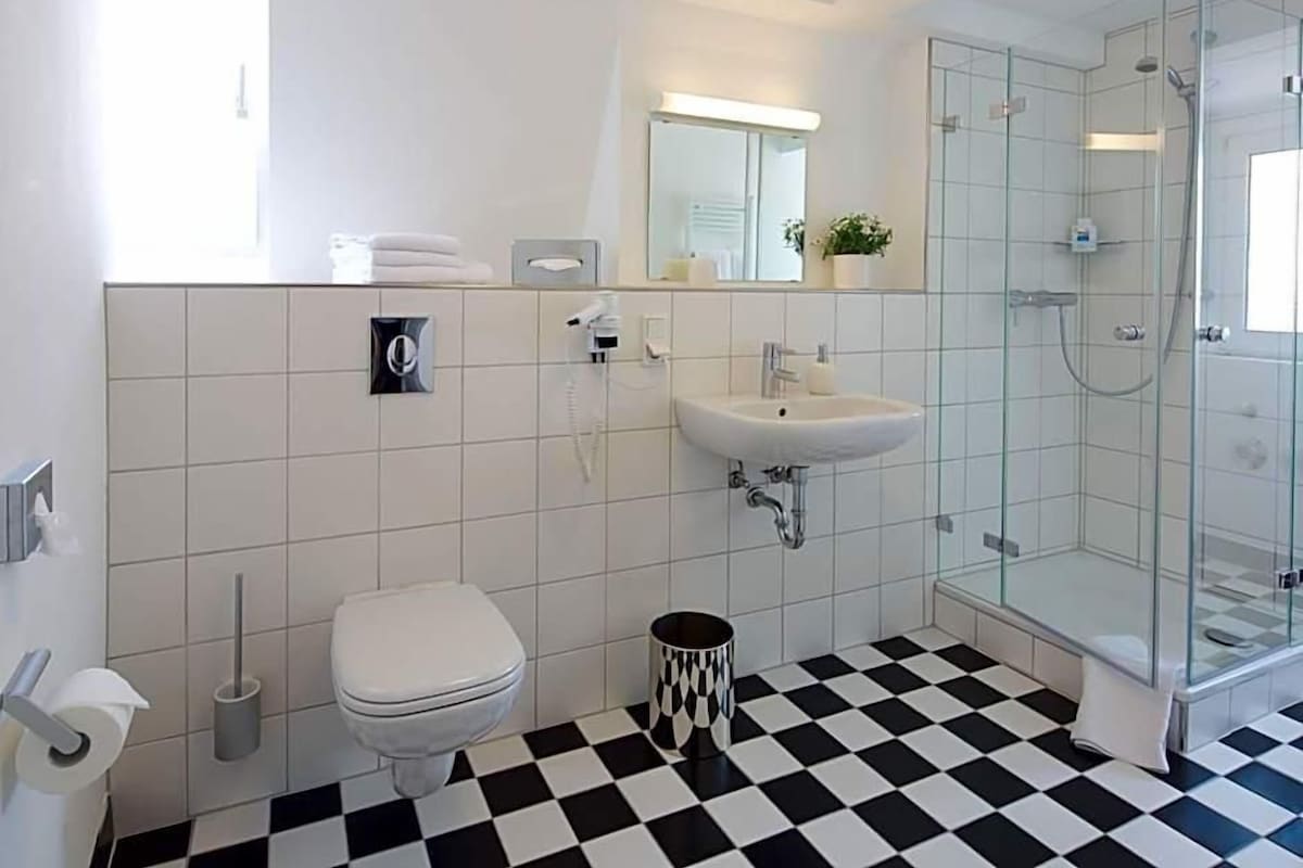 A modern bathroom with a toilet, sink, and glass-enclosed shower.