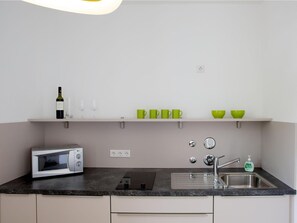 Una cocina moderna con microondas, fregadero y una botella de vino sobre la encimera.