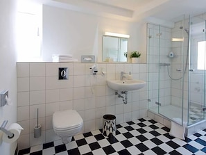Une salle de bain moderne équipée de toilettes, d’un lavabo et d’une douche à parois de verre.