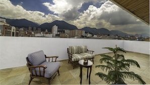 A rooftop terrace with a view of a cityscape and mountains.
