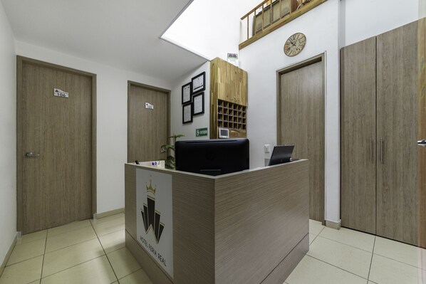 A hotel reception desk with a wooden finish, a clock on the wall, and a sign indicating room number 106.