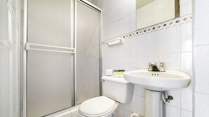 A bathroom with a toilet, a sink, and a shower enclosure. - Hotel Elegant Suite (Bogotá)