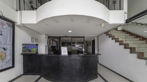 A reception area with a curved black marble counter, a map on the wall, and a staircase to the right. - Hotel Elegant Suite (Bogotá)