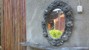 Un baño con un lavamanos blanco, un espejo decorativo y una puerta de madera.