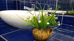 Et badeværelse med en hvid vask, en trævase med blomster og blå flisegulve.
