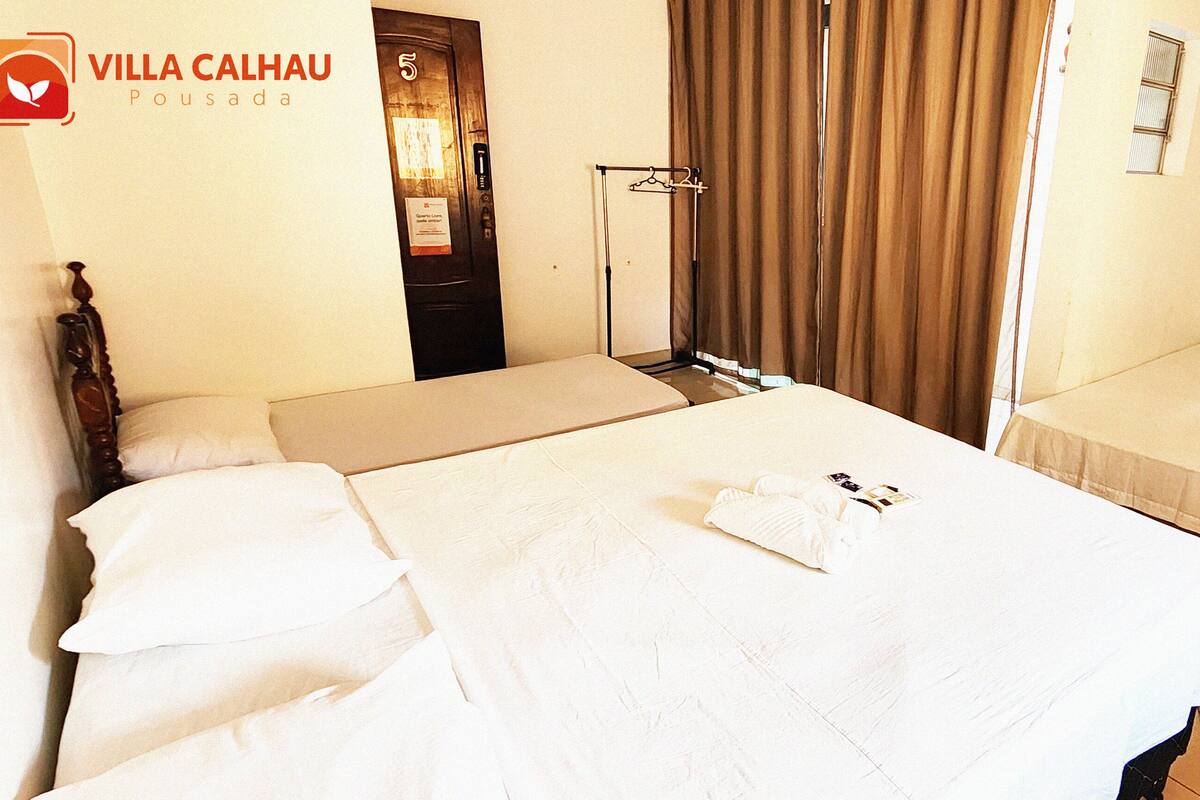 Ein Hotelzimmer mit zwei Betten, einem Schrank, einem Spiegel und einem mit Vorhängen versehenen Fenster.