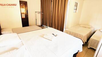 Habitación de hotel con dos camas, un armario, un espejo y una ventana con cortinas.
