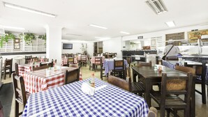 A restaurant with checkered tablecloths, wooden chairs, and a kitchen area. - Ayenda 1120 Comercial (Pereira)