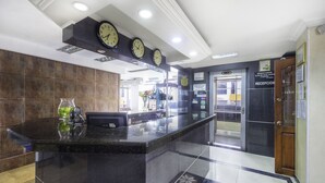 A hotel reception area with a marble counter, clocks, and a reception desk. - Ayenda 1120 Comercial (Pereira)