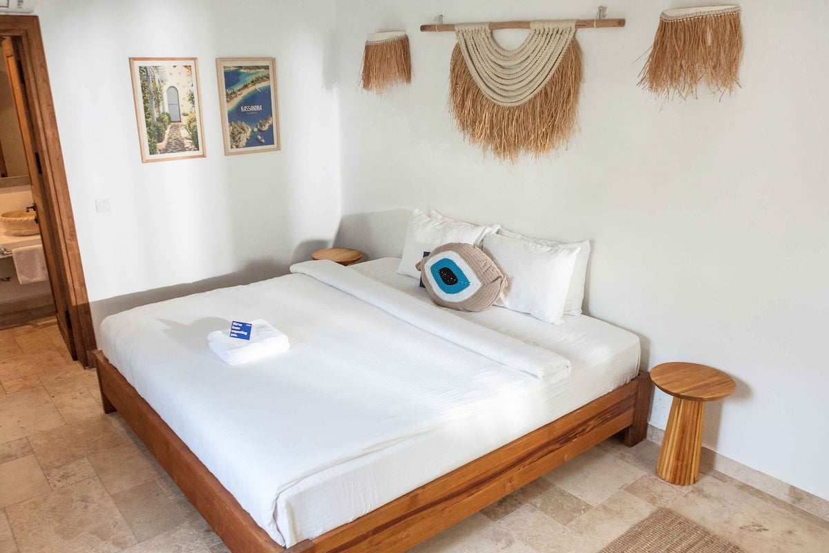 A neatly made bed with a white comforter, a wooden headboard, and a small bedside table with a lamp.