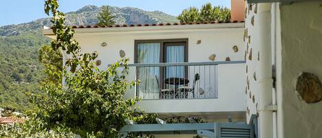 Ein Balkon mit Stuhl und Tisch mit Blick auf eine gebirgige Landschaft.