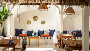 A cozy outdoor seating area with wooden furniture, a thatched roof, and decorative wall art. - Kassandra Ölüdeniz  (Fethiye)