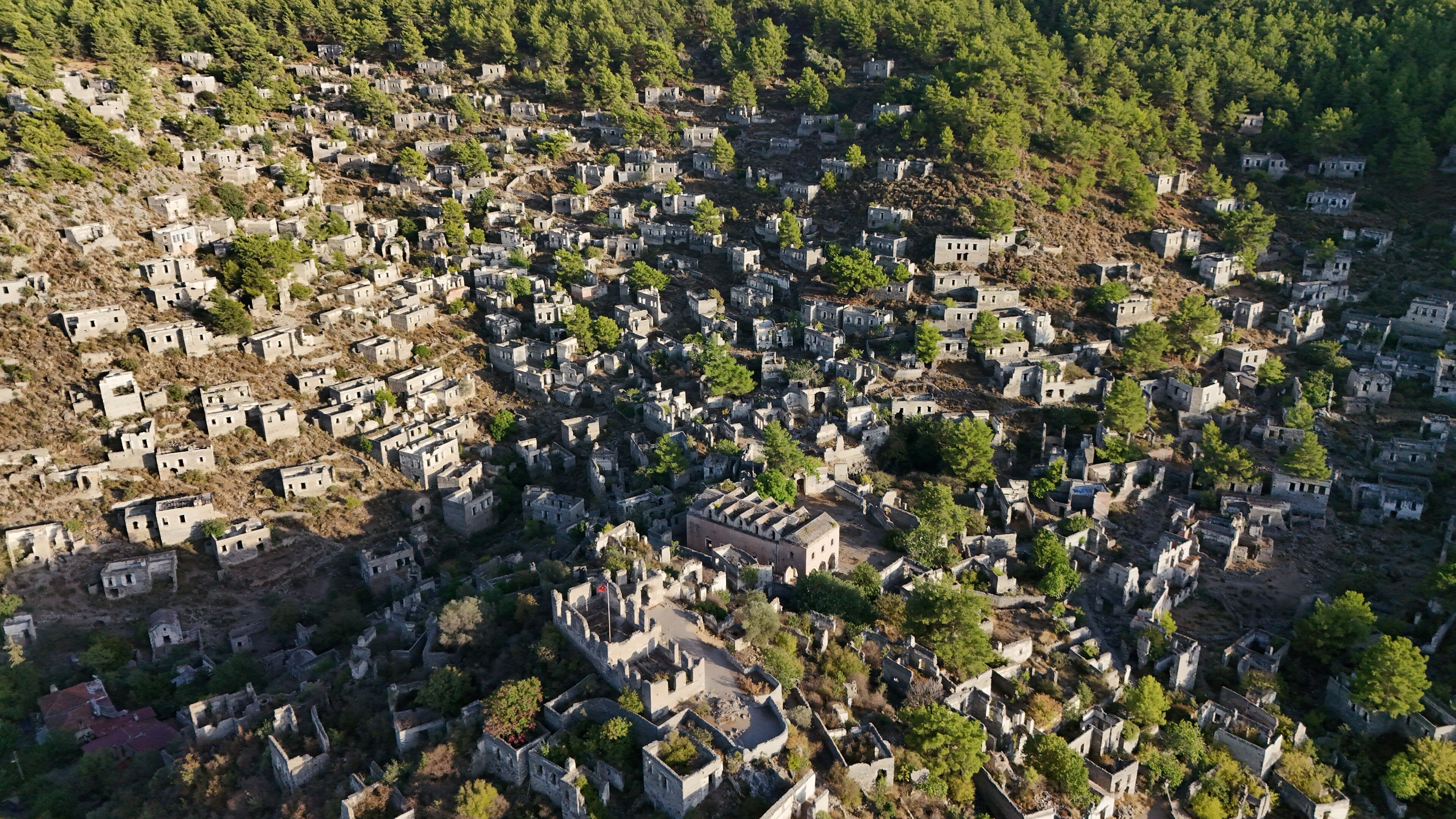 Eine Vogelperspektive auf ein historisches Dorf mit Steinhäusern, engen Gassen und üppiger Vegetation.