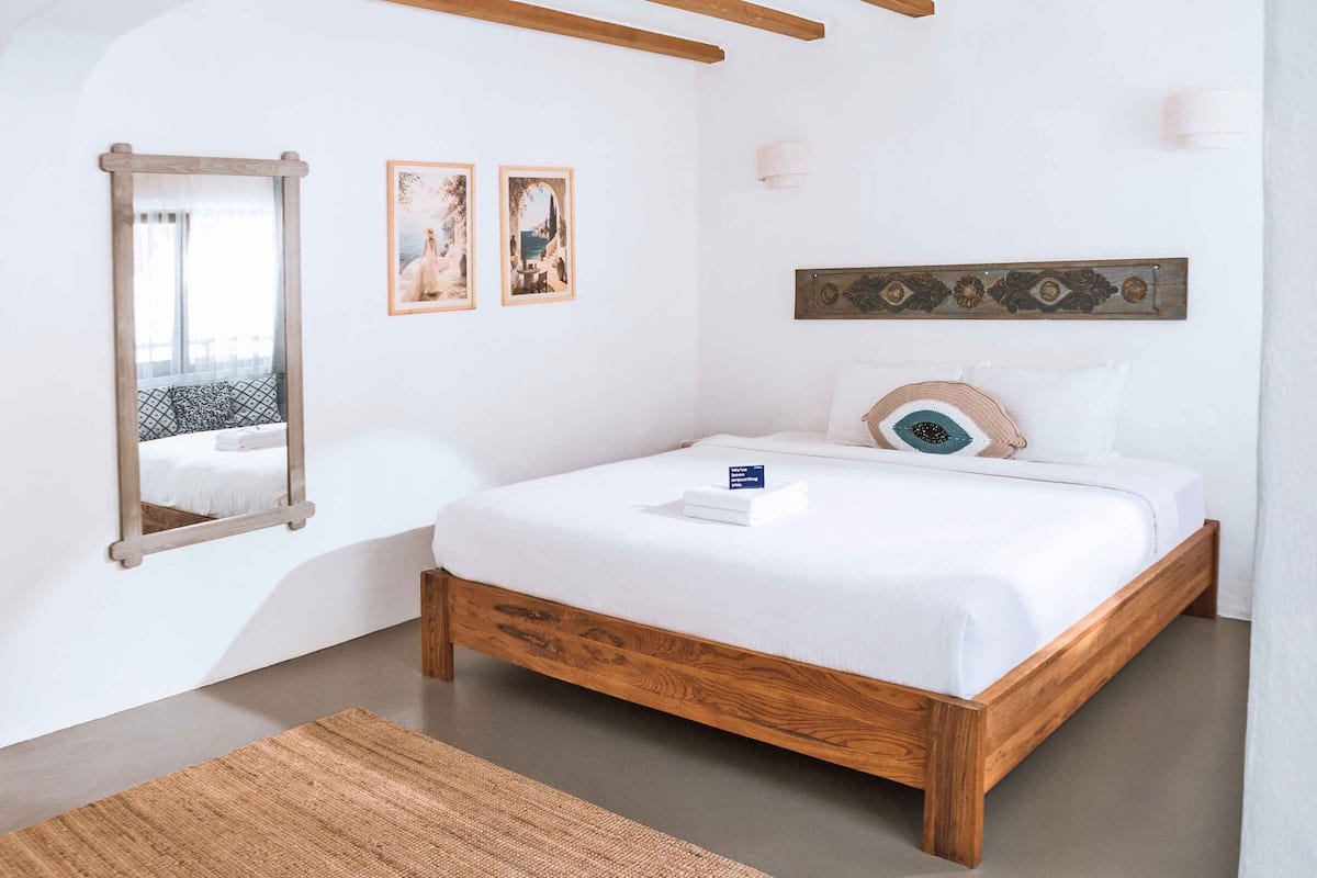 A bedroom with a wooden bed, a large mirror, and two framed pictures on the wall.