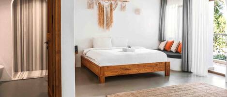 A bedroom with a wooden bed, a wall-mounted macrame piece, and a view of the outdoors.