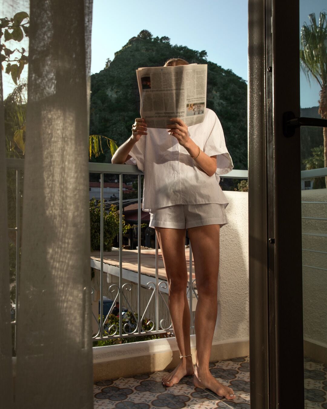 A person standing on a balcony with a newspaper.