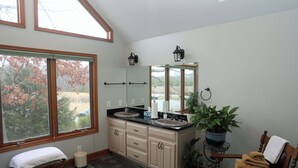 A bathroom with a large window, a sink, a mirror, and a towel rack. - Villa Cathedral (Alton)