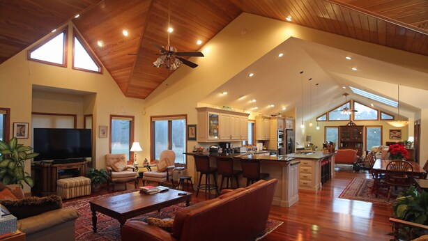 A spacious living area with a high ceiling, wooden flooring, and a large window providing natural light. - Villa Cathedral (Alton)