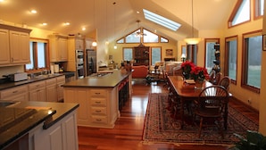 A spacious kitchen with a large island, wooden cabinets, and a dining area with a rug and chairs. - Villa Cathedral (Alton)