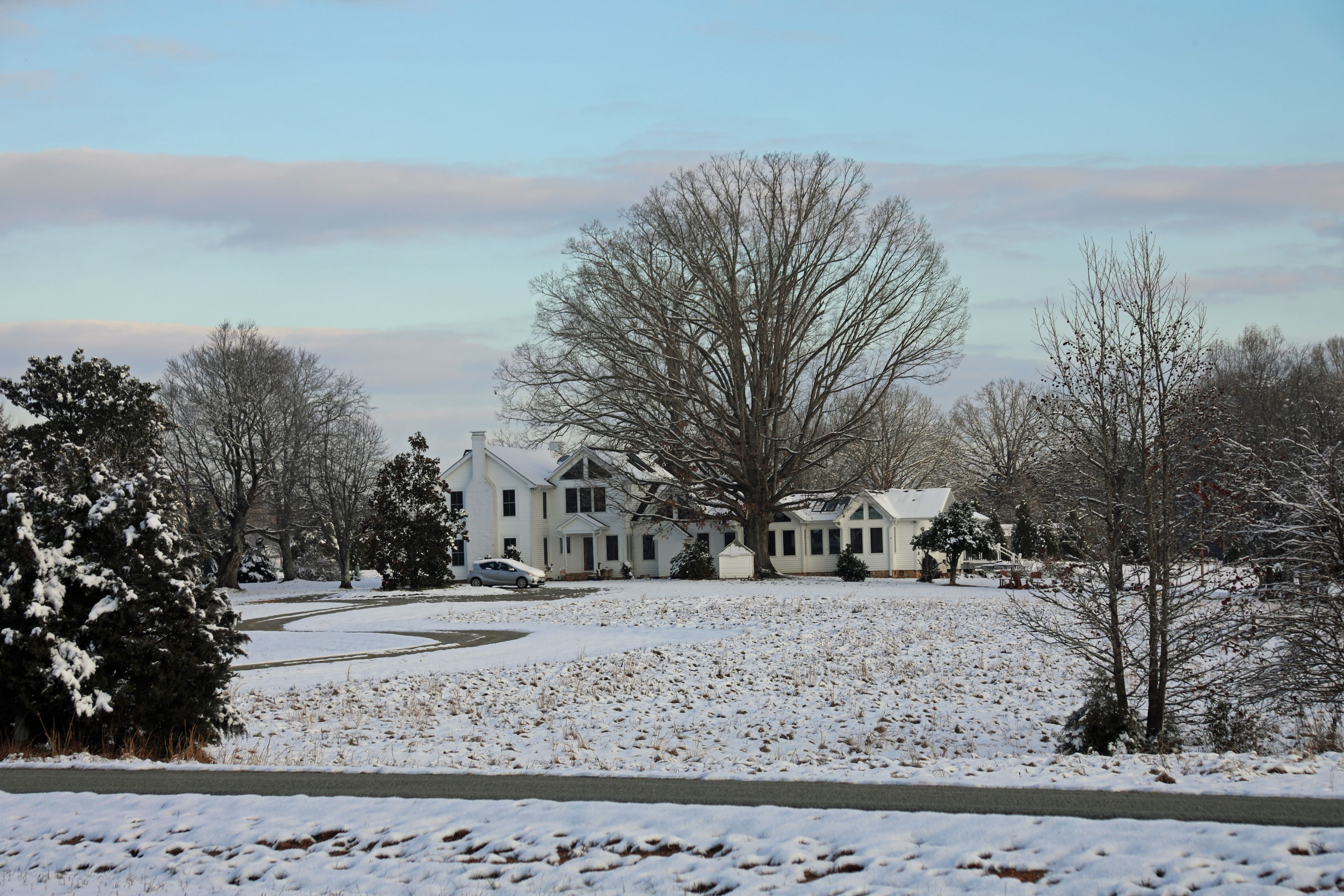 A large, single-story house with a symmetrical facade, surrounded by snow-covered ground and leafless trees.