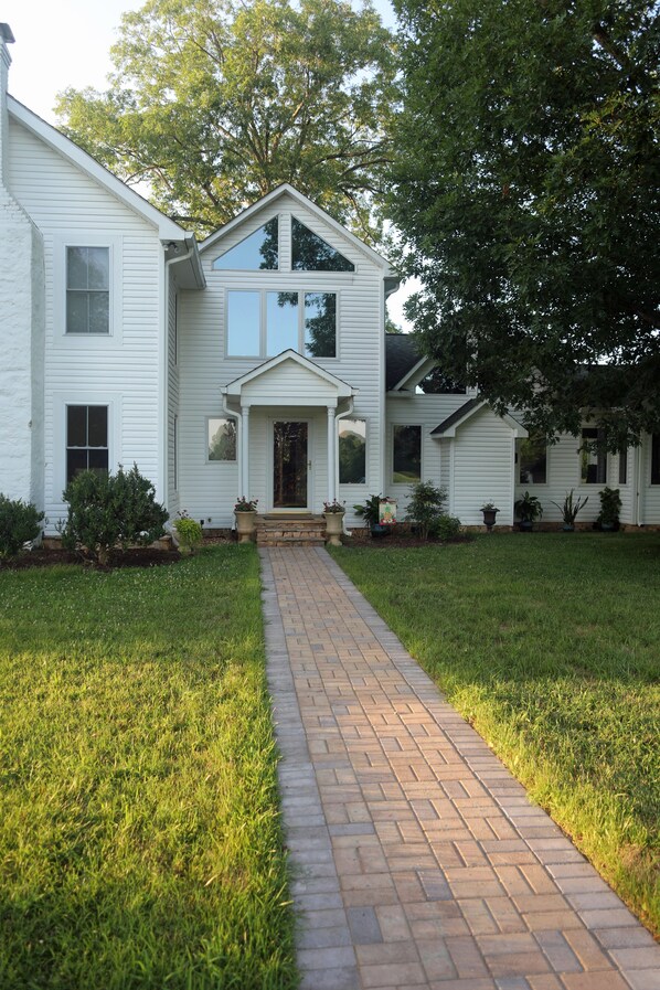 A two-story white house with a brick pathway leading to the front door. - Villa Cathedral (Alton)