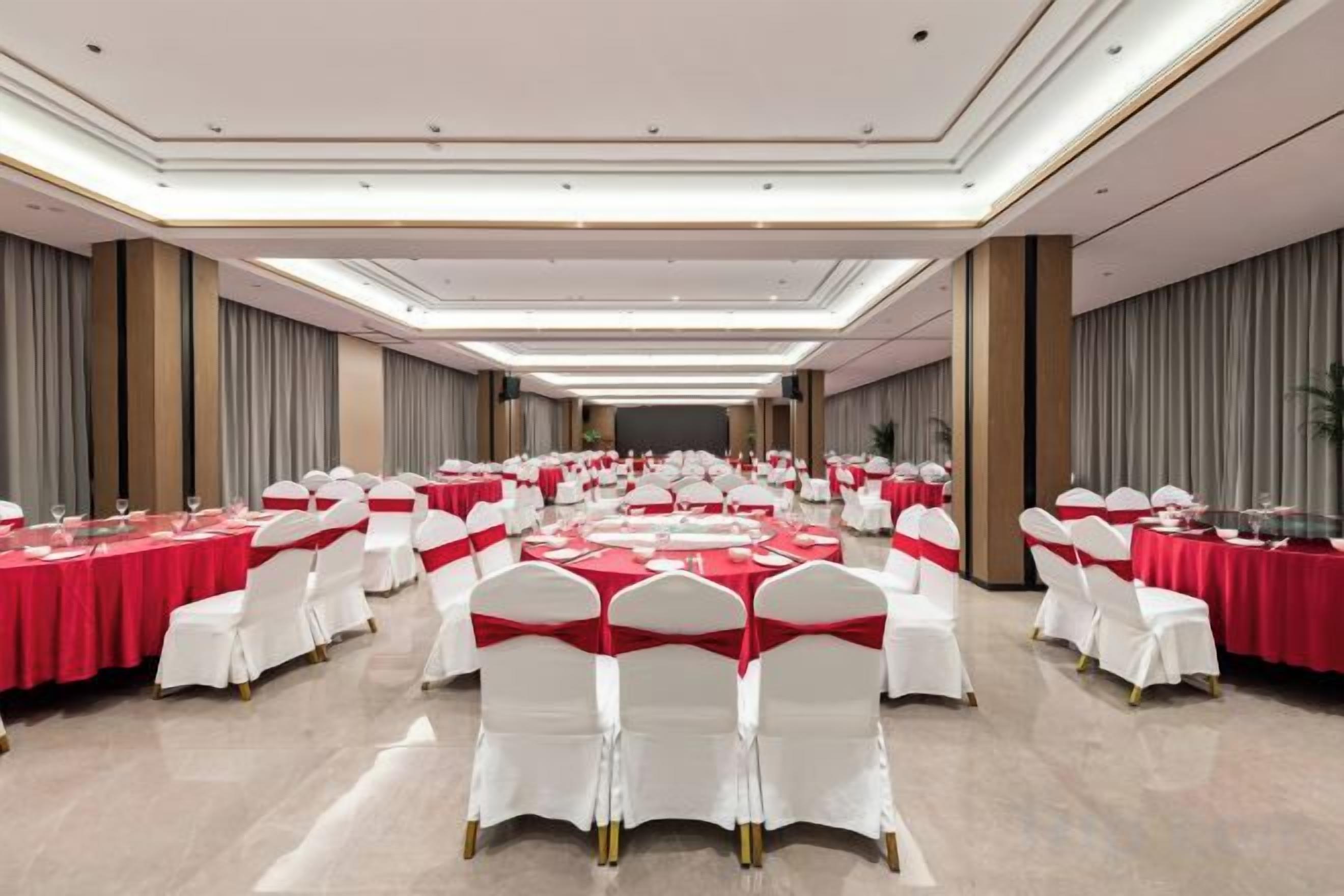 A banquet hall with round tables and white chairs, arranged in rows.