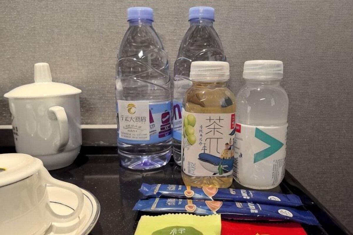 Ein Tisch mit einem weißen Teekessel, zwei Wasserflaschen, einer Teeflasche und einigen Snacks.