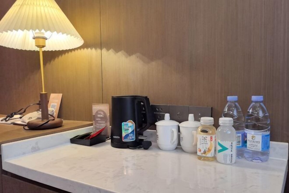 Ein Hotelzimmerzähler mit Lampe, einer Kaffeemaschine, einer Tasse und abgefülltem Wasser.