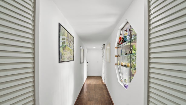A narrow hallway with white walls, wooden flooring, and a glass display case with decorative items. - Beautiful House Fantastic View Azusa California (Azusa)