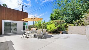 A patio with a table and chairs, a sliding glass door, and a wooden building. - Beautiful House Fantastic View Azusa California (Azusa)