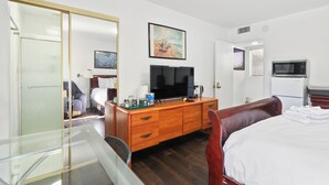 A hotel room with a bed, a wooden dresser, a television, a microwave, and a painting on the wall. - Beautiful House Fantastic View Azusa California (Azusa)