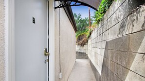 A narrow concrete pathway leading to a white door with a brass handle and a small 'B' marking. - Beautiful House Fantastic View Azusa California (Azusa)