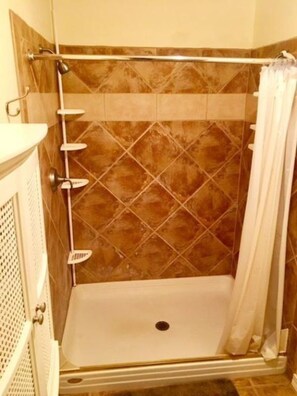 A shower area with a tiled wall, a showerhead, and a curtain. - Telles House (Angel Fire)