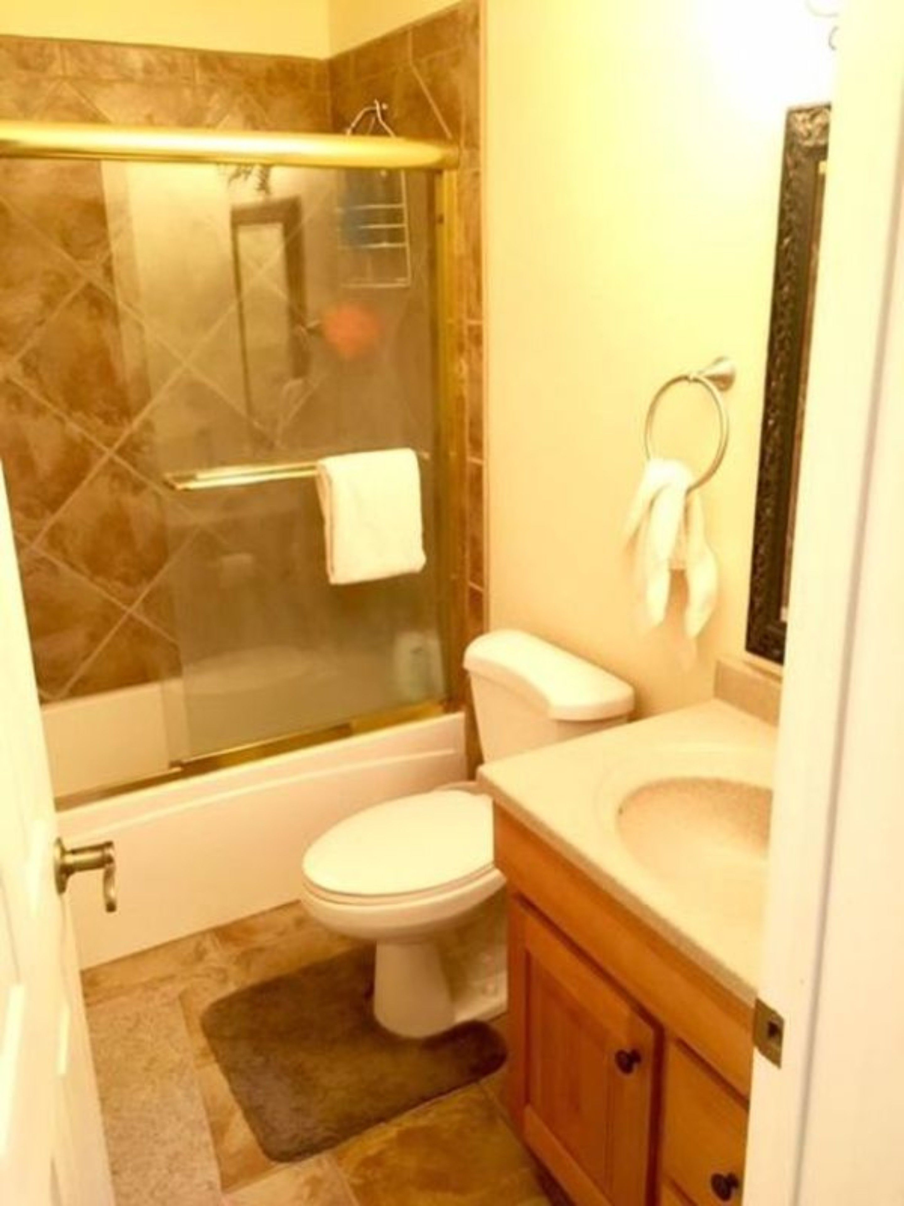 A bathroom with a glass-enclosed shower, a toilet, a sink, and a mirror.