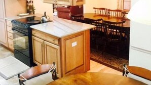 Une cuisine dotée de meubles en bois, d’un four à micro-ondes, d’une cuisinière et d’un coin repas avec une table et des chaises.