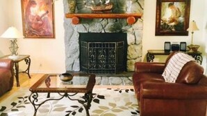 Un salon chaleureux avec une cheminée en pierre, un canapé en cuir et une table basse.