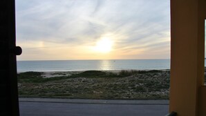 Vista del océano al atardecer desde un balcón con barandilla.