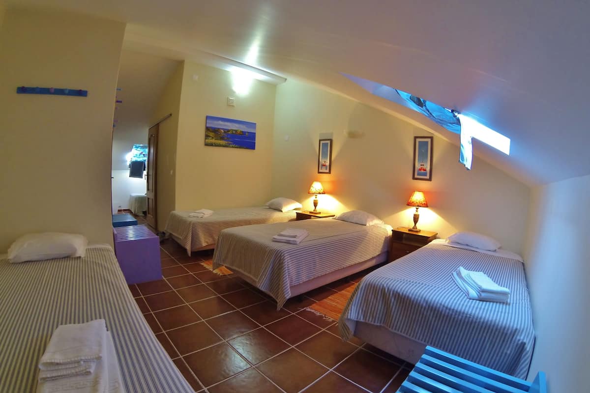 A hotel room with two single beds, a sofa, a small table, and a bathroom visible through an open door.
