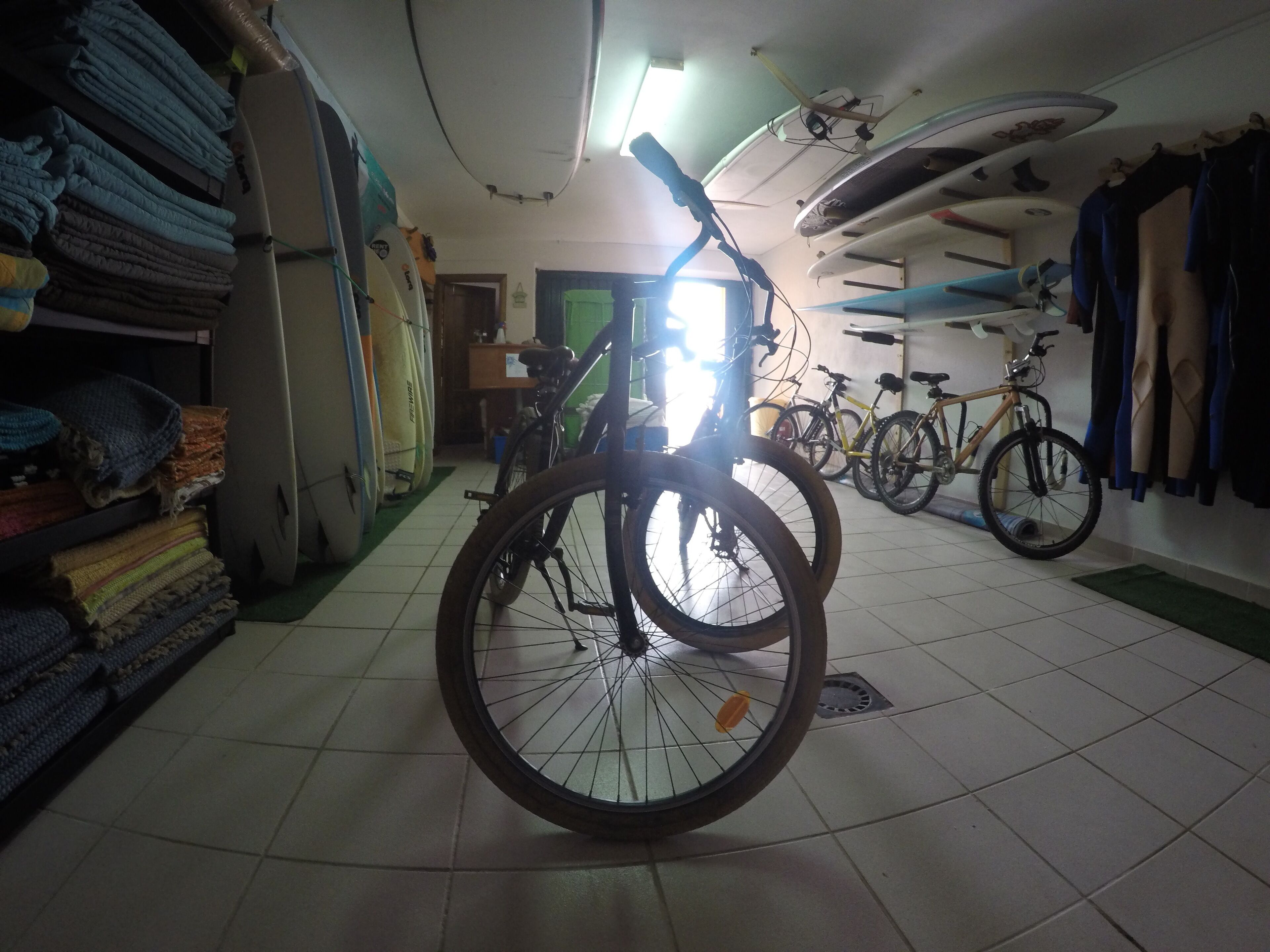 A room with bicycles, surfboards, and folded blankets.