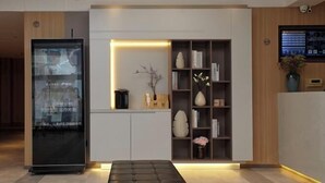 A modern reception area with a glass display case, a seating area, and a bookshelf with decorative items. - Homeinn Hotel (Yangzhou Shouxihu Wenchang Pavilion) (Yangzhou)