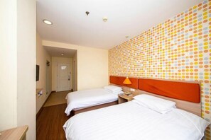 A hotel room with two beds, a wooden headboard, a wall with a polka dot pattern, and a small table with a lamp. - Homeinn Hotel (Yangzhou Shouxihu Wenchang Pavilion) (Yangzhou)