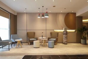 A modern lobby with seating arrangements, a reception desk, and a decorative column. - Homeinn Hotel (Yangzhou Shouxihu Wenchang Pavilion) (Yangzhou)