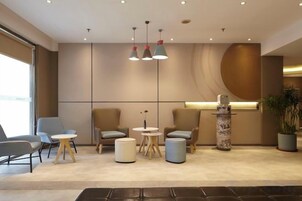 Un vestíbulo moderno con arreglos de asientos, una recepción y una columna decorativa.