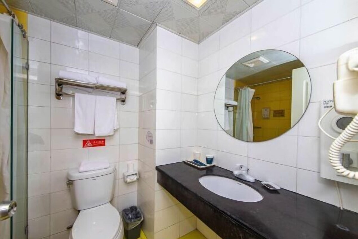 A bathroom with a white toilet, a black sink, a mirror, and a telephone.